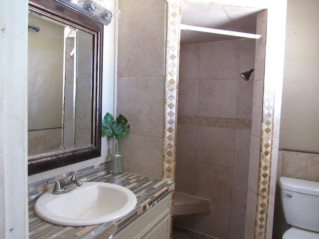 full bathroom featuring toilet, tiled shower, and vanity