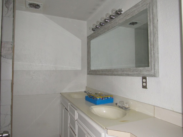 bathroom with double vanity, visible vents, and a sink