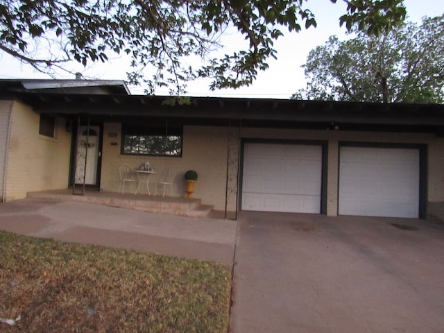 exterior space featuring an attached garage, concrete driveway, and brick siding