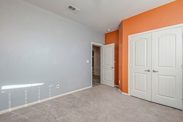 unfurnished bedroom with a closet and light carpet