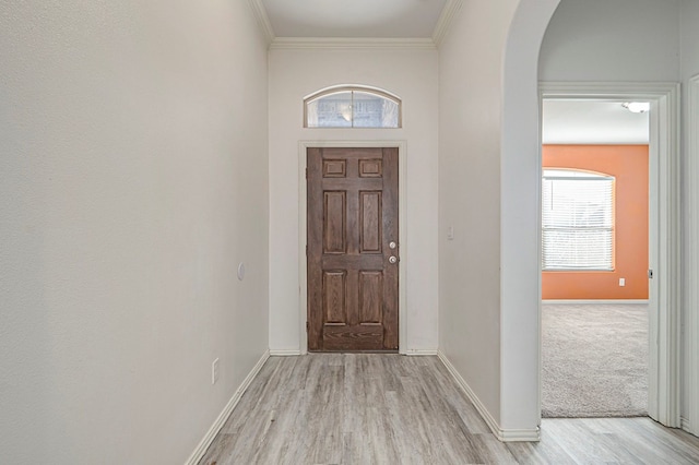 foyer entrance with crown molding and light wood-type flooring