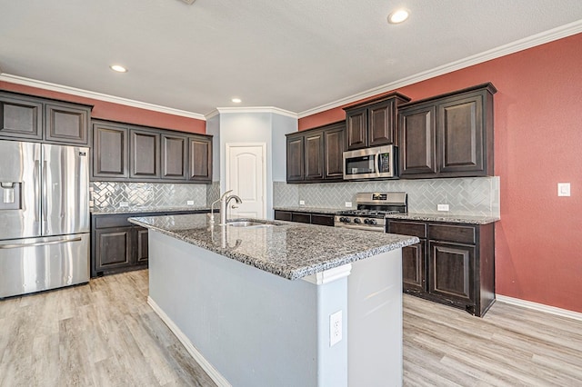 kitchen with light hardwood / wood-style floors, sink, dark brown cabinetry, an island with sink, and stainless steel appliances