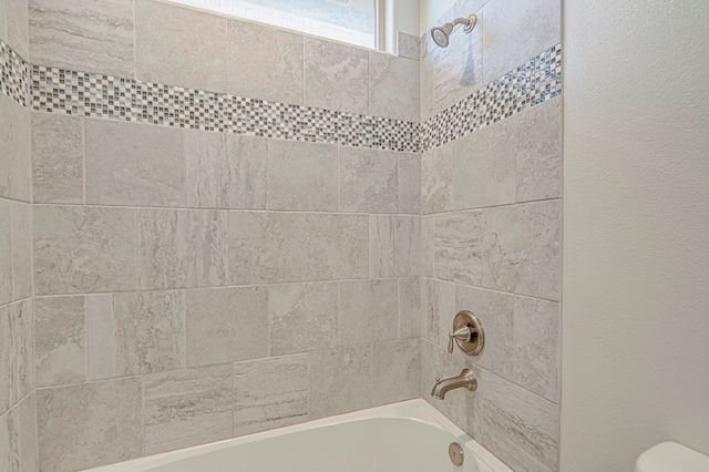 bathroom featuring toilet and tiled shower / bath combo