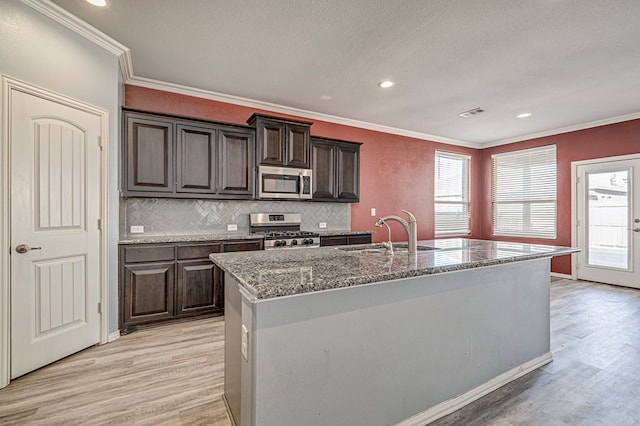 kitchen featuring sink, dark brown cabinets, light wood-type flooring, an island with sink, and stainless steel appliances