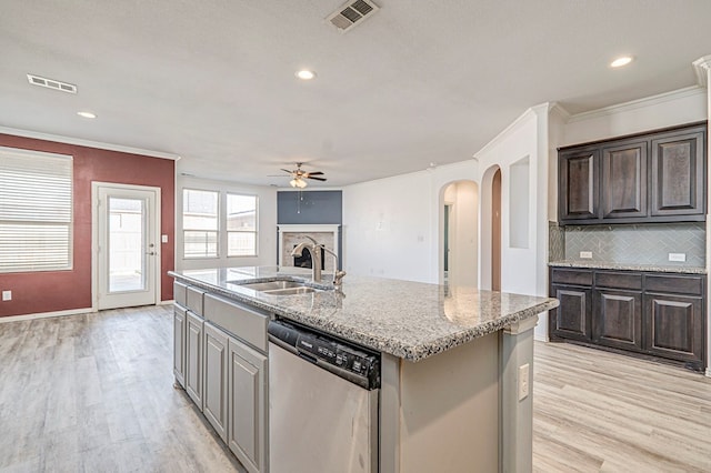 kitchen with light hardwood / wood-style floors, tasteful backsplash, dishwasher, a kitchen island with sink, and sink