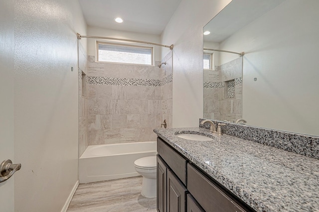 full bathroom featuring tiled shower / bath combo, wood-type flooring, toilet, and vanity