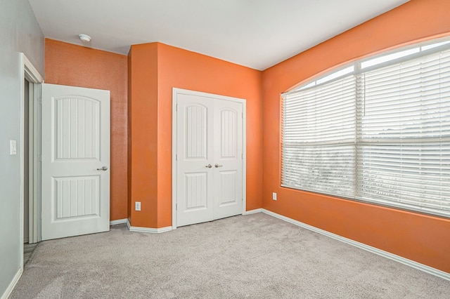 unfurnished bedroom featuring a closet and light colored carpet