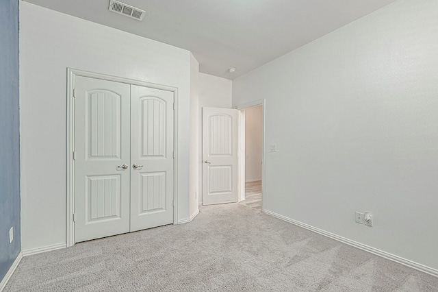 unfurnished bedroom with a closet and light colored carpet