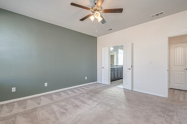 unfurnished bedroom featuring light colored carpet, ceiling fan, and ensuite bathroom