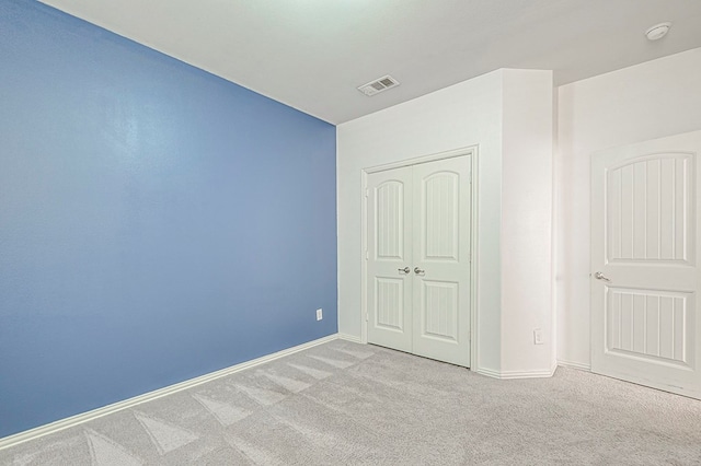 unfurnished bedroom featuring light colored carpet and a closet