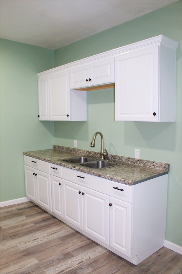 kitchen featuring light wood-type flooring, white cabinetry, and sink