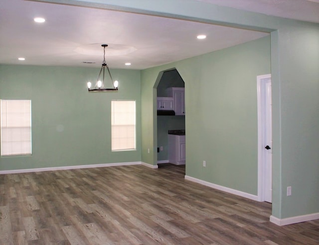 unfurnished room with a notable chandelier and dark hardwood / wood-style flooring