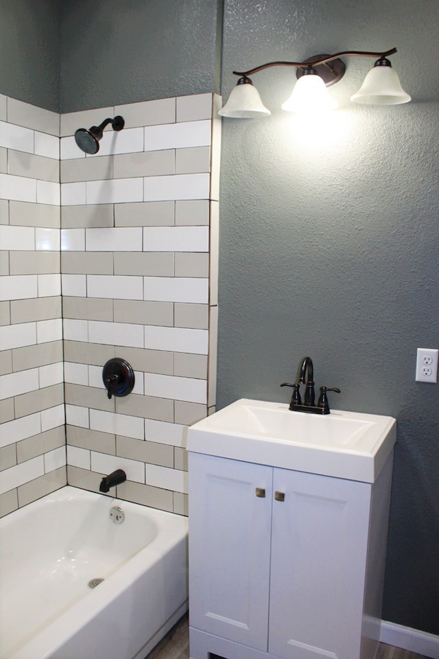 bathroom with tiled shower / bath combo and vanity