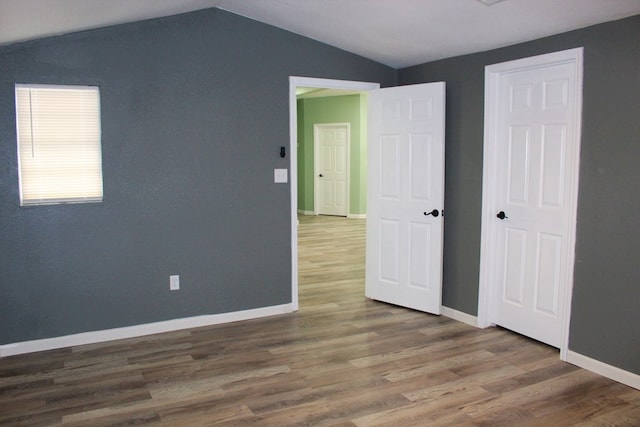 spare room featuring hardwood / wood-style floors and vaulted ceiling