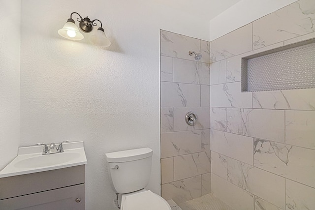 bathroom featuring vanity, tiled shower, and toilet