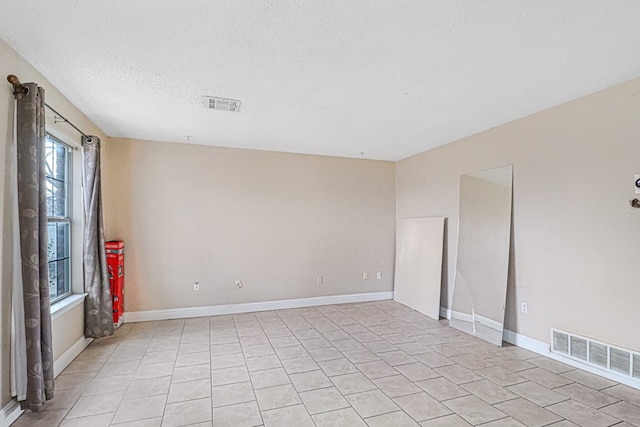 spare room with light tile patterned flooring and a textured ceiling