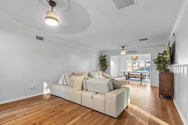 living room featuring light hardwood / wood-style floors, ceiling fan, and crown molding