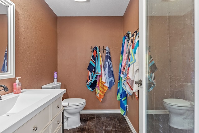 bathroom featuring vanity, hardwood / wood-style floors, a textured ceiling, and toilet