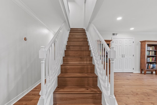 stairway featuring hardwood / wood-style floors and ornamental molding