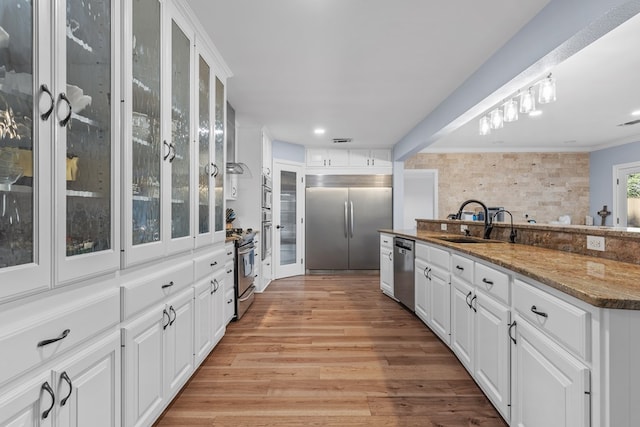 kitchen featuring light hardwood / wood-style floors, white cabinetry, dark stone counters, and appliances with stainless steel finishes