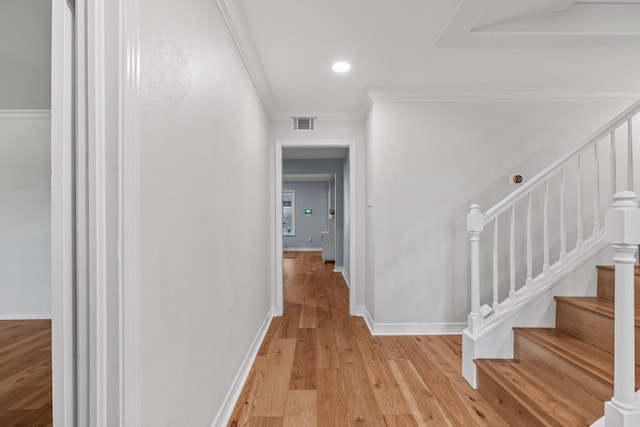 hallway with ornamental molding and light hardwood / wood-style flooring