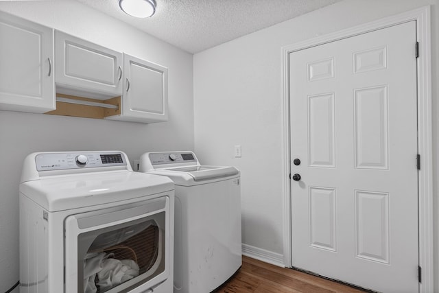 washroom featuring a textured ceiling, separate washer and dryer, cabinets, and dark hardwood / wood-style floors