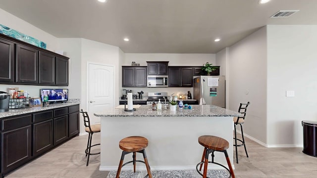 kitchen with a center island with sink, dark brown cabinets, and stainless steel appliances