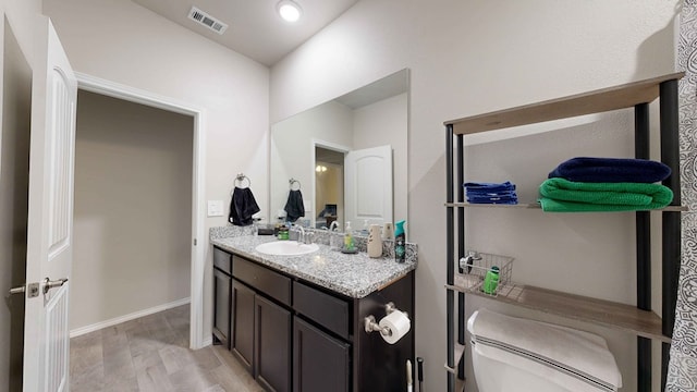 bathroom with wood-type flooring, toilet, and vanity