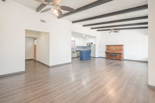 unfurnished living room featuring hardwood / wood-style flooring, ceiling fan, and beam ceiling