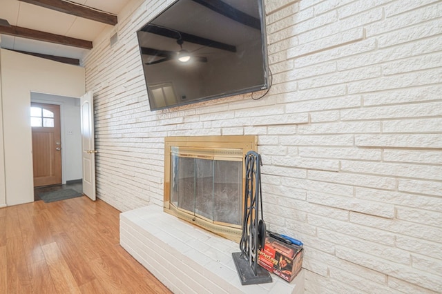 unfurnished living room with beamed ceiling, brick wall, and light wood-type flooring