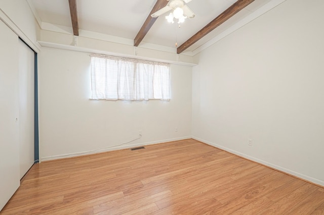 empty room with beam ceiling, light hardwood / wood-style floors, and ceiling fan