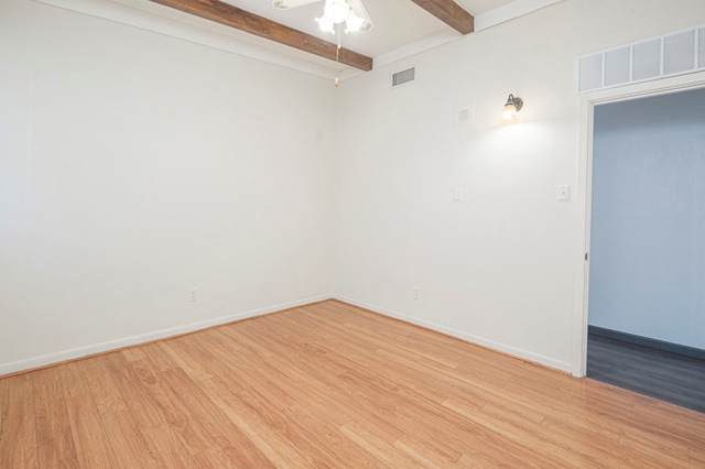 spare room featuring light hardwood / wood-style flooring and beamed ceiling