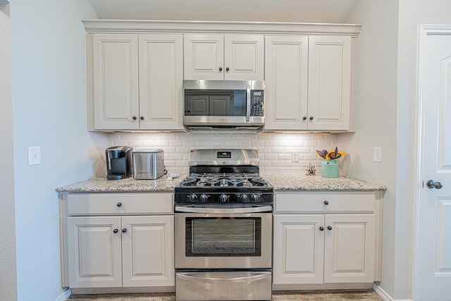 2812 Carver, Midland, TX 79705 - kitchen featuring appliances with stainless steel finishes, baseboards, decorative backsplash, and light stone countertops