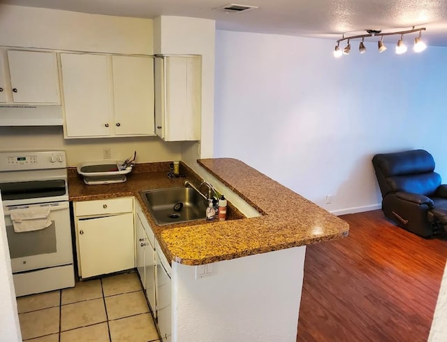 kitchen with sink, ventilation hood, kitchen peninsula, white cabinets, and white stove