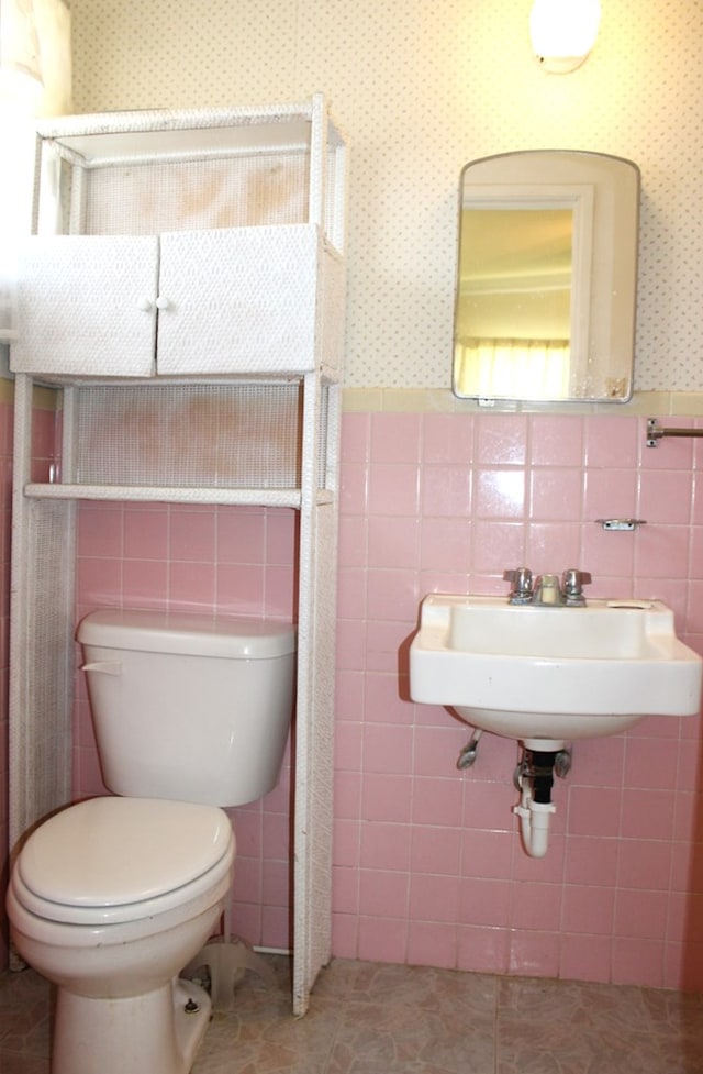 bathroom with tile patterned floors, toilet, sink, and tile walls