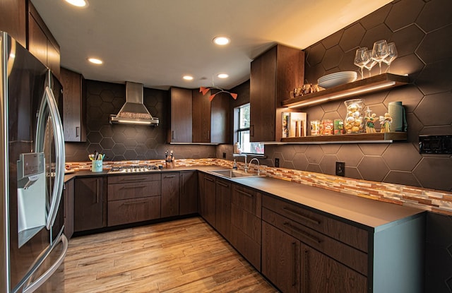 kitchen featuring backsplash, sink, light hardwood / wood-style flooring, wall chimney exhaust hood, and stainless steel appliances