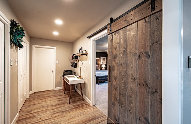 hall featuring a barn door and light hardwood / wood-style flooring