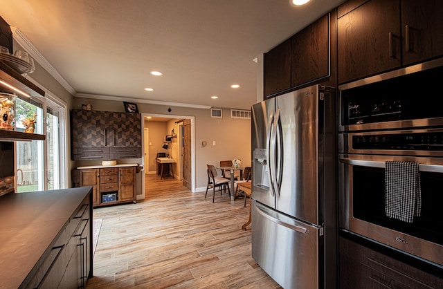 kitchen with stainless steel appliances, ornamental molding, and light hardwood / wood-style floors