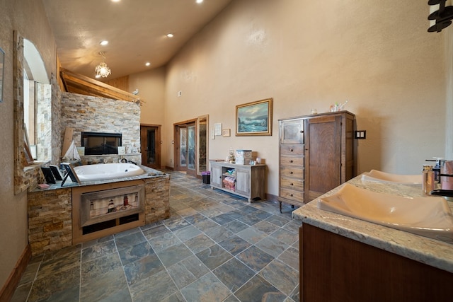 bathroom with vanity, a bath, a high ceiling, and a chandelier