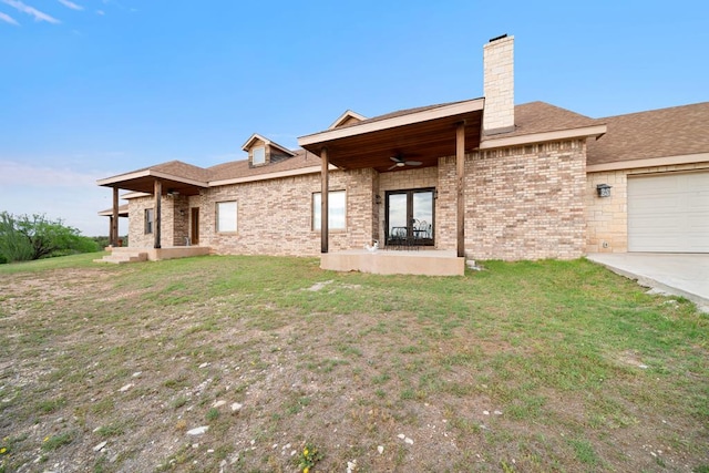 back of house featuring a lawn, ceiling fan, and a garage