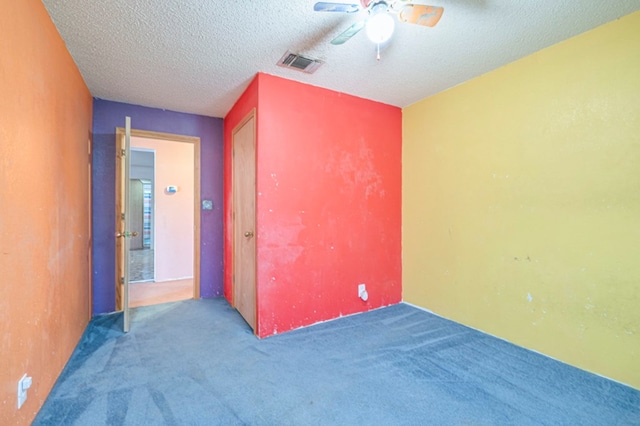 carpeted spare room with ceiling fan and a textured ceiling