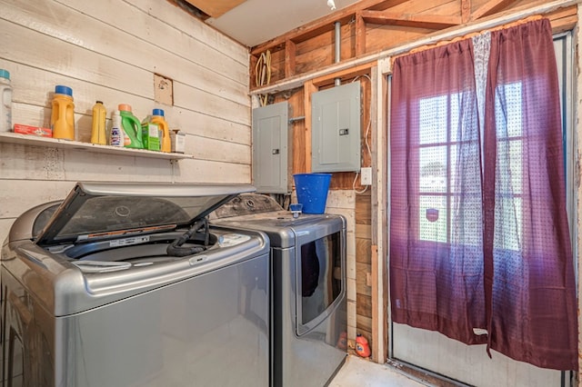 clothes washing area with independent washer and dryer, electric panel, and wood walls