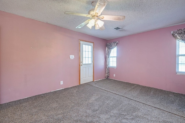 empty room with carpet flooring, ceiling fan, and a textured ceiling