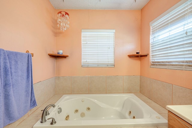 bathroom with vanity, a textured ceiling, and tiled tub