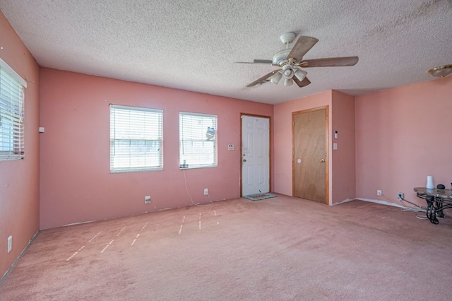 spare room featuring a textured ceiling, ceiling fan, and light carpet