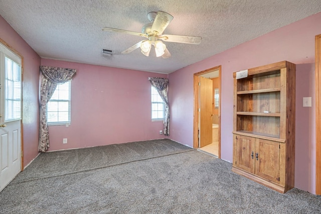 carpeted spare room featuring ceiling fan, plenty of natural light, and a textured ceiling