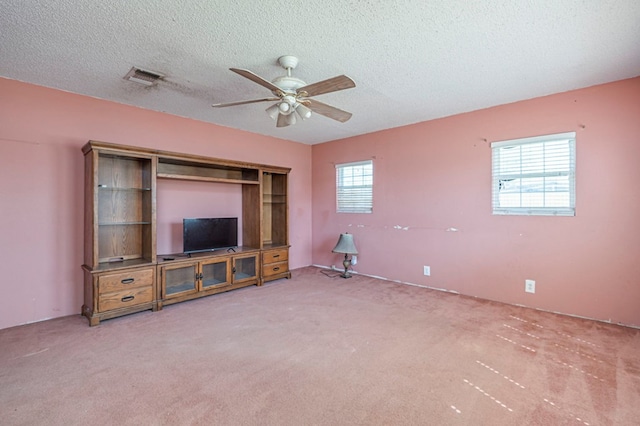 unfurnished living room featuring ceiling fan, carpet floors, and a textured ceiling