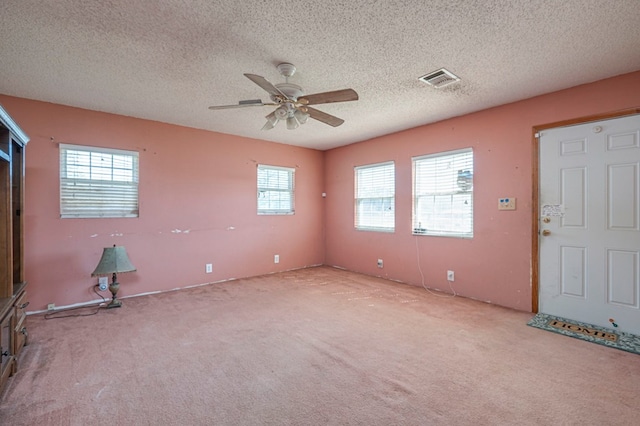 carpeted spare room featuring a textured ceiling and ceiling fan