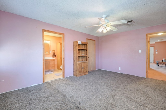 unfurnished bedroom featuring carpet flooring, ceiling fan, a textured ceiling, and connected bathroom