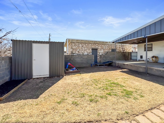 view of yard featuring an outbuilding, a storage unit, a patio area, and a fenced backyard